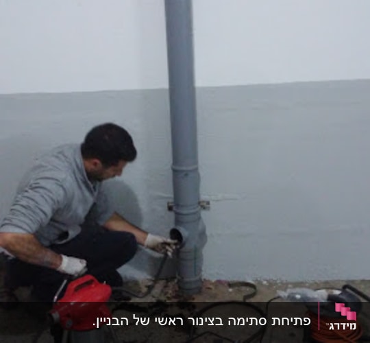 אדם עובד על צינור ביוב עם כלים